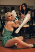 Blonde blowing bubble gum while fisting the brunette who is texting.