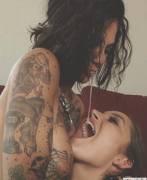 Tattooed chick spits a load into her friend's mouth
