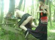 Gipsy in a dress pegging a guy in the woods