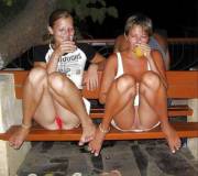 Mother and daughter drink alcohol with legs on the bench
