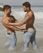 Felipe Lei and Leon Noronha playing in ocean with their jeans on
