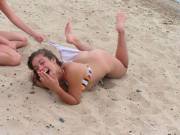 Playfully removing her bikini bottom on the beach