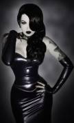 Pretty tattooed brunette with a black latex outfit: long skirt, bustier and fingerless gloves.