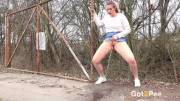 Nikki Dream holds onto an old gate before enjoying a pee standing