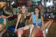 A couple girls sitting spread eagle on bar stools.
