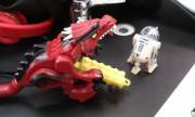 R2-D2 watches a Wingless Dragon take a lego car from behind