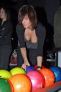 Down-blouse with a nipple slip reaching for a bowling ball.