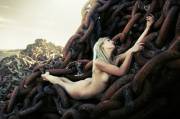 Blonde laying on enormous rusty chains