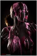 Glowing pink paint dripping on nude girl's breasts
