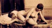 two women in bed, mostly nude other than striped socks; shoes. 1883