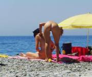 Naked girl applying suntan lotion on her friend's body