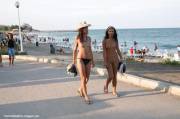 Two scantily dressed chicks walking by the beach