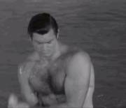 Vintage-looking gif of a hot, beefy guy feeling up his hairy chest and getting wet