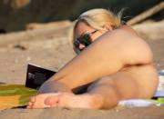 Naked beach girl reading a book