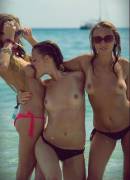3 girls in bikini bottoms with 1 girl biting another girls breast.