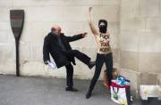 Topless protester being kicked by an old man.