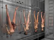 Four naked women on a slaughterhouse conveyor belt